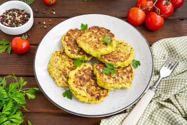 vegetable zucchini pancakes with cheese dill and parsley on a plate with sour cream copy space - Драники с кабачками