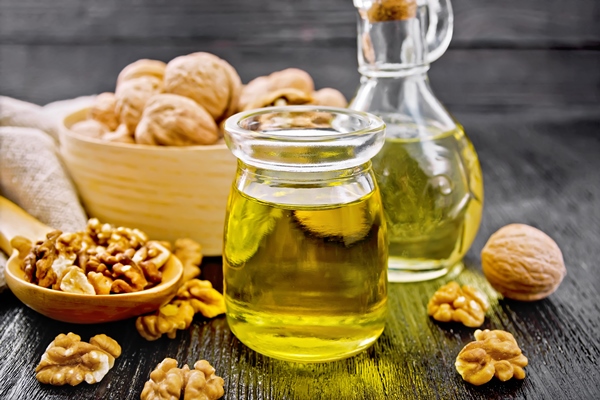 walnut oil in jar and decanter nuts in box spoon and on table on wooden board background - Борщ с грибными голубцами, постный стол