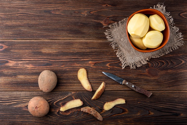 woman hands peel potato clean potatoes on wooden surface repairing food for cooking 1 - Драники с овсяными хлопьями