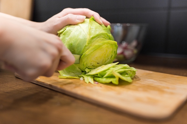 young woman in the kitchen cutting fresh cabbage - Суп из сладкого перца с капустой