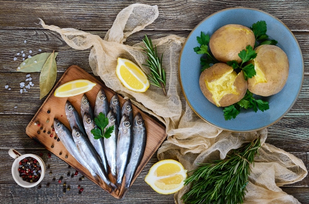 boiled unpeeled potatoes in skins a small salted fish of baltic herring sprats on a wooden table top view flat lay - Картофель "в мундире"