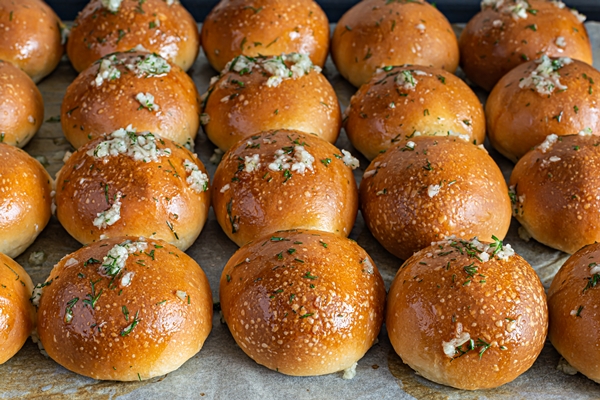 freshly baked buns pampushki with garlic and dill for the first course soup on a baking tray - Чесночные постные булочки