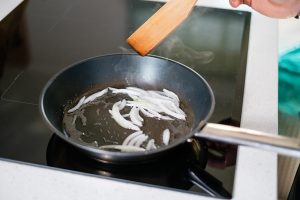 frying onions in a pan on an induction stove - Постная рыбная кулебяка
