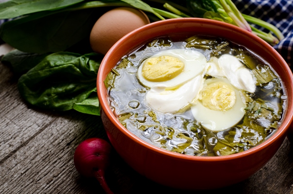 green borscht with sorrel spinach and potato topped with boiled egg and sour cream on a vintage wooden table - Борщ зелёный украинский