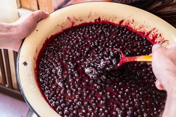 hands stir with wooden spoon jam from blueberries in metal basin traditional sweet dessert - «Варенье-пятиминутка» из черники