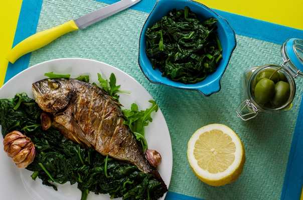 healthy dinner or lunch with baked dorada fish or sea bream garnished with spinach in a bowl on blue background - Рыба со шпинатом, постный стол