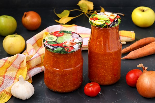 homemade adzhika with tomatoes apples and carrots in jars on a dark background harvesting for the winter - Яблочно-сливовая аджика