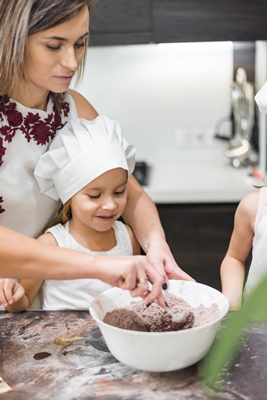 kids standing in front of mother while mixing cocoa powder in bowl on messy kitchen counter - Пирожное "Картошка"