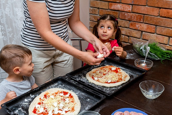little boy and girl helping mom make pizza at home - Учим детей готовить