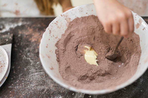 person s hand mixing butter and cocoa powder in bowl using spoon - Пирожное "Картошка"