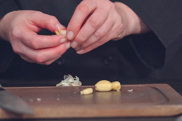 step by step dicing organic garlic on wood cutting board - Постный соус чатни из яблок