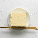 top view of butter on white plate and golden knife - Правила составления меню
