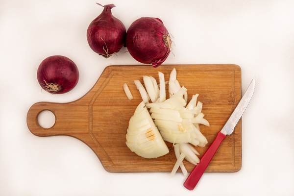 top view of fresh white onion on a wooden kitchen board with knife with red onions isolated on a white surface - Праздничная солянка по-монастырски