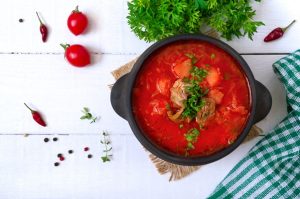 traditional ukrainian borsch with young vegetables and meat in a black clay pot on a white wooden surface - Правила составления меню