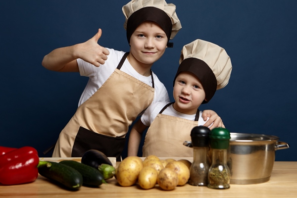 two children siblings wearing chef uniform preparing dinner in the kitchen confident boy showing thumbs up and hugging his little brother ready to make delicious meal out of fresh organic vegetables - Картофель печёный (в кожуре)