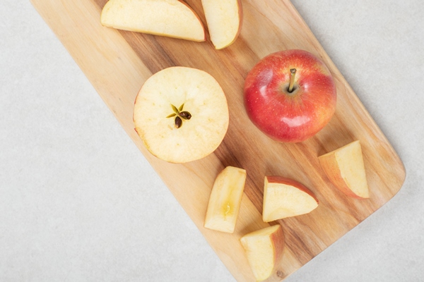 whole and slices of red apple on wooden board - Яблочные цукаты
