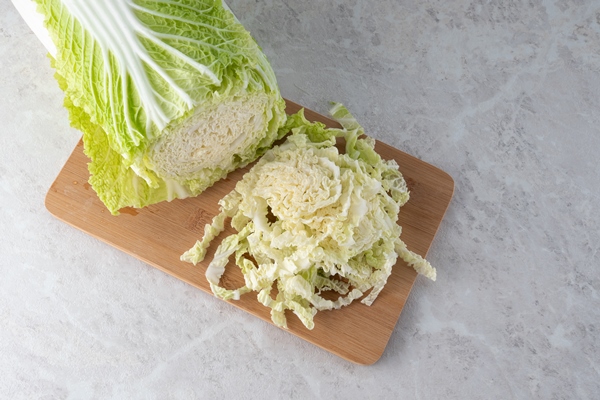 a fresh head of peking cabbage is chopped to make a salad marble background - Салат из пекинской капусты с сухофруктами