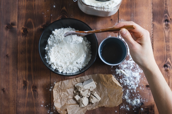 a woman s hand mixing sourdough with a wooden spoon bakery concept - Пита
