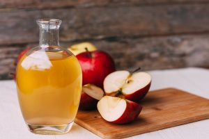 apple organic vinegar in glass pitcher with ripe fresh red and yellow apples on wooden background - Морс из яблок