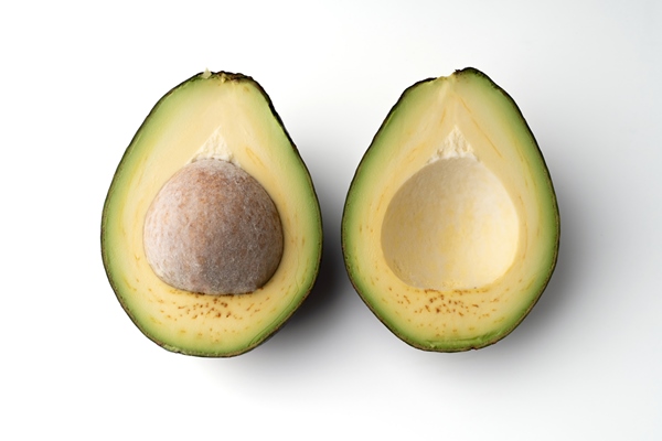 avocado cut in half isolated on a white background the flesh of the avocado is creamy and soft with a buttery taste avocados contain nutrients vitamins and good fats - Бутерброды с авокадо, лососем и кунжутом