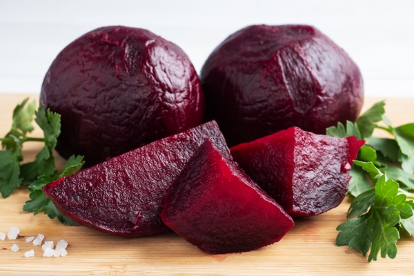 boiled beets whole and cut on a cutting board with parsley leaves on a white background - Галеты со свекольным хумусом