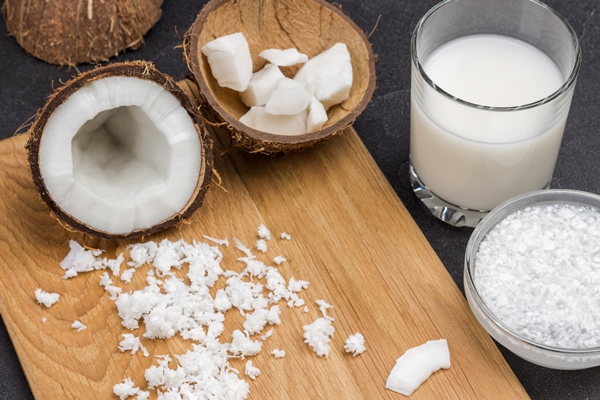 coconut milk in glass and bowl coconut flakes half fresh coconut - Постные оладьи из кокоса и банана