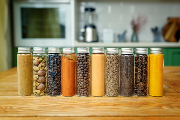 different spices in glass flasks for spices on the table in home kitchen with copy space - Постные имбирные человечки