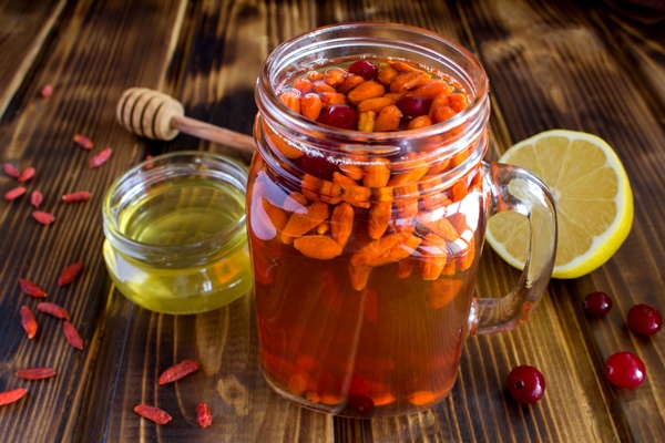 drink with goji berries and cranberry on the brown wooden background - Чай с ягодами годжи и лимоном