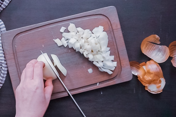 flat lay step by step dicing yellow onion on a wood cutting board - Постный салат из кальмаров