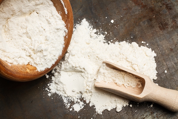 flour in a wooden bowl with a wooden spoon on a metal table - Апельсиновый пирог