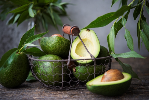fresh green avocado with leaves on wooden space - Бутерброды с авокадо чесноком и пряными травами