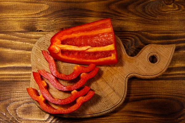 fresh red pepper on cutting board on wooden table - Салат из нута со сладким перцем