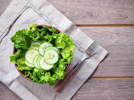 fresh salad lettuce with cucumber slices on wooden table - Постные роллы из лаваша с овощами