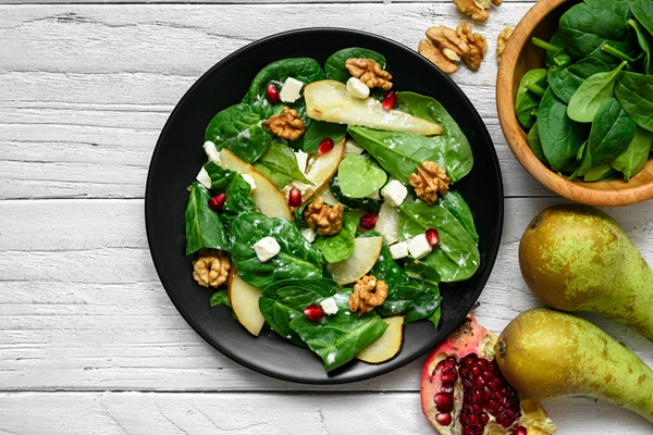 fresh spring salad with spinach leaves pear nuts pomegranate and feta cheese in black plate 1 - Салат с грушей, орехами, шпинатом и тофу