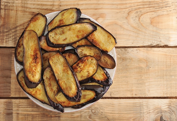 fried eggplant on the plate on rustic wooden surface - Постные баклажанные рулеты с орехами
