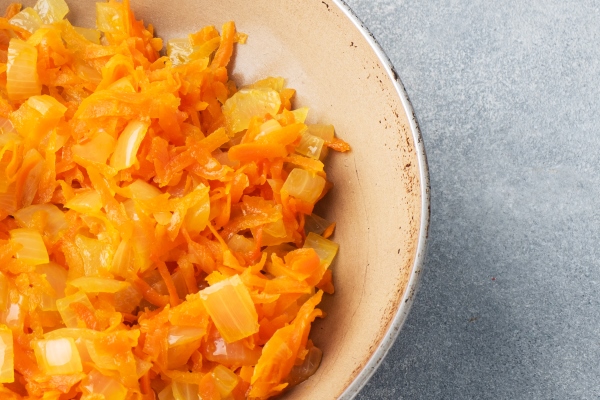 fry grated carrots and chopped onions with oil in a frying pan gray concrete table copy space - Томатный суп с чечевицей