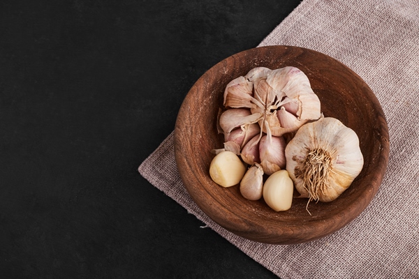 garlic cloves in a wooden cup top view - Постные макароны с креветками и чесноком