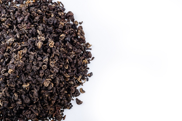 heap of black tea on a white background dry black tea leaves isolated on white background - Чай с боярышниковым цветом