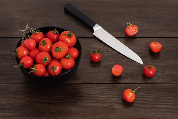 homegrown cherry tomatoes in a black bowl on a dark wooden table with a sharp knife next to it - Постные тако с фасолью и овощами