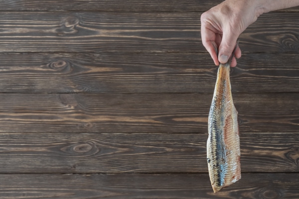 male hand holding fillet of herring - Малосольная селёдка домашняя с луком