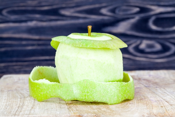 peeled green apple on a wooden cutting board closeup of food of natural production - Рисовый постный пудинг с яблоками