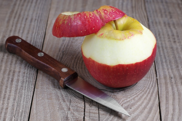 peeled red apple and knife on rustic wooden table - Постный салат из кальмаров