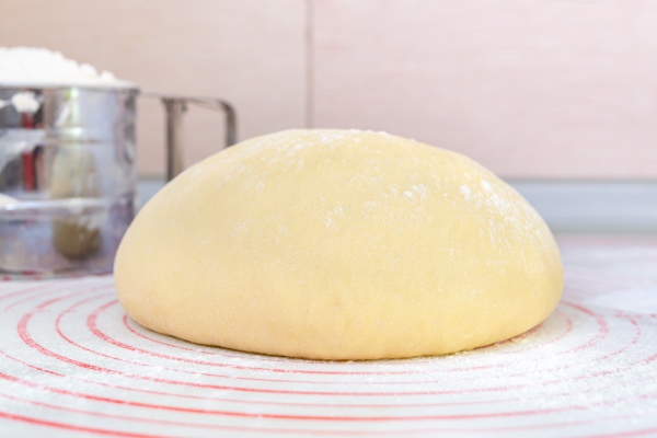 raw yeast dough on a special silicone baking mat for rolling dough on the kitchen table preparation of dough for pizza pie baking and other bakery products the concept of home baking - Лобиани