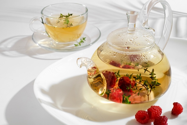 red herbal berry tea with thyme and fresh raspberry in glass teapot white background with copyspace - Чай с малиной