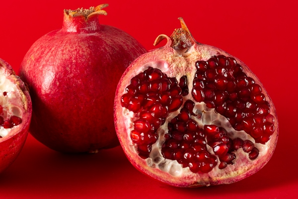 ripe pomegranates with whole pomegranate isolated on a red background - Салат с грушей, орехами, шпинатом и тофу