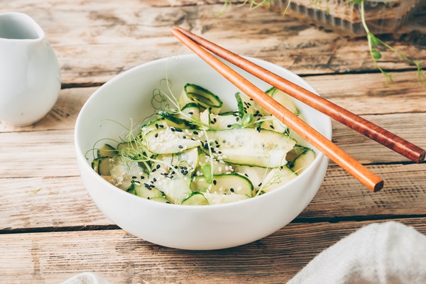salad of sliced cucumbers with herbs and sesame seeds in a white bowl - Основы сухоядения