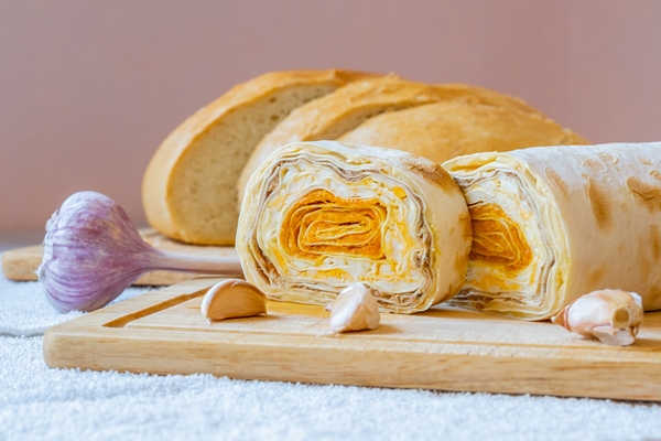 sliced roll of armenian pita bread with carrot filling on a wooden board - Лаваш с фасолью