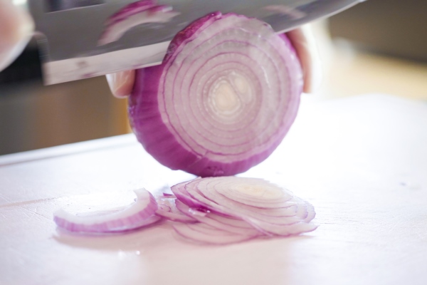 slicing purple onion on a white cutting board - Салат из грейпфрута и креветок