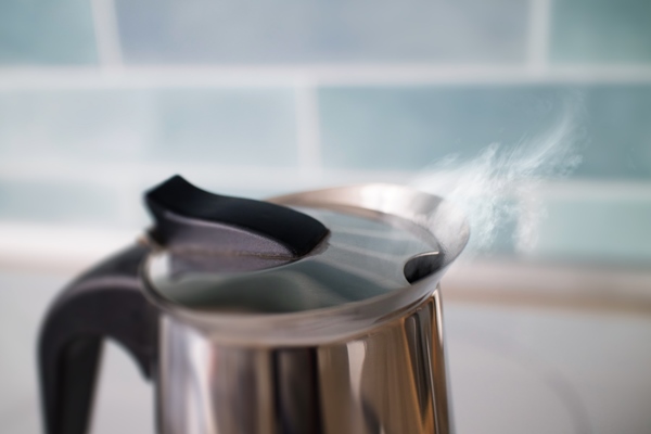 tea kettle with boiling hot steaming drinking water and steam from it against a blue tile in the kitchen - Чай с фруктами и корицей