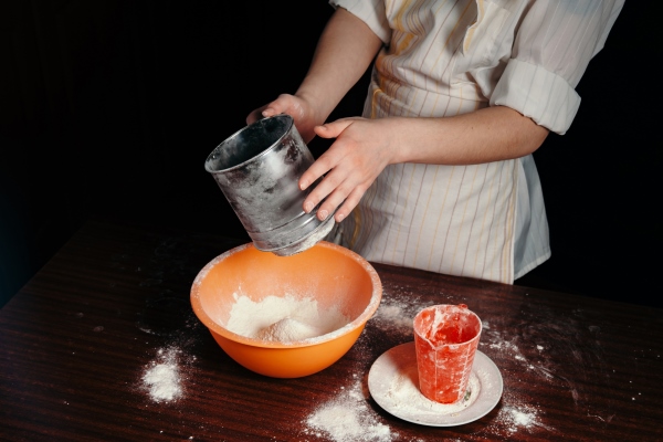 the girl sifts the flour in a steel sieve bright kitchen items - Творожный кулич